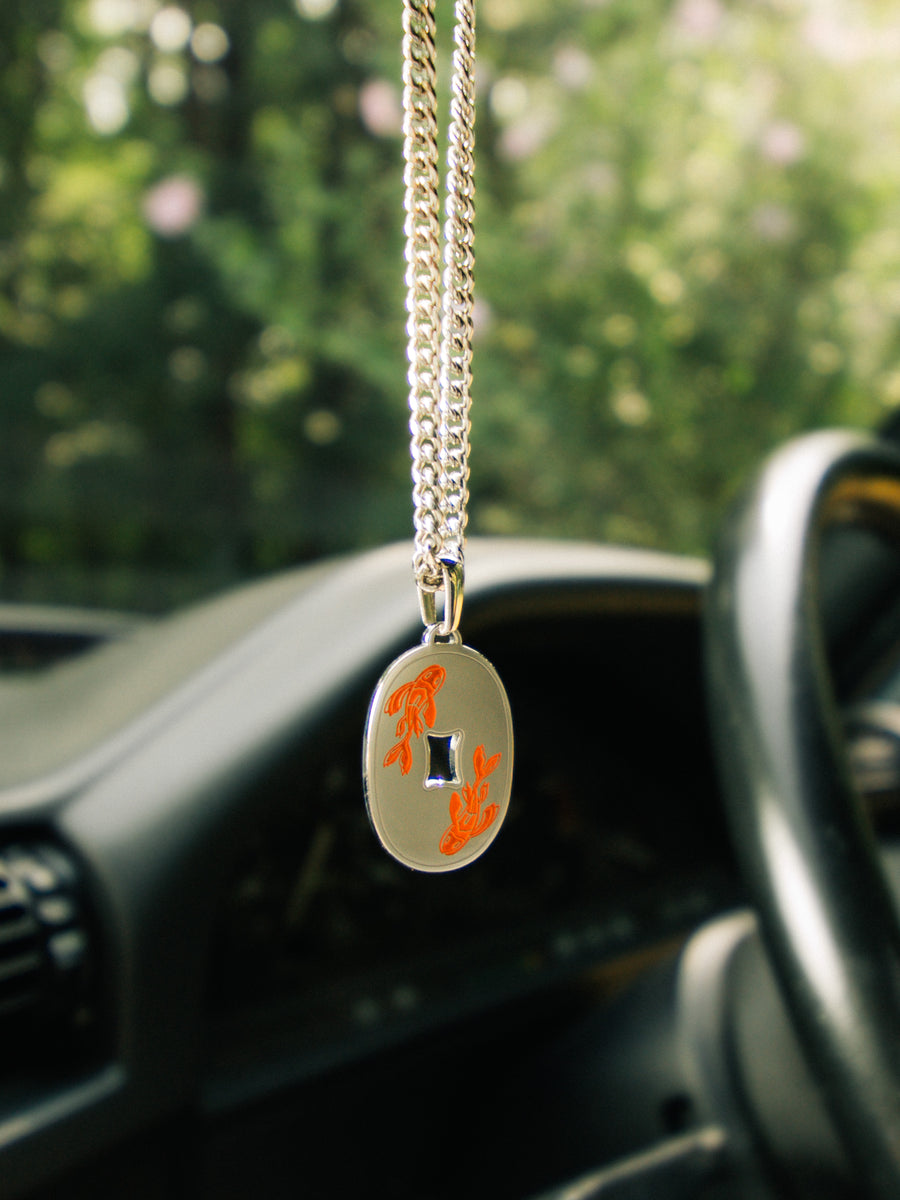 Koi Fish Necklace resting on a car body