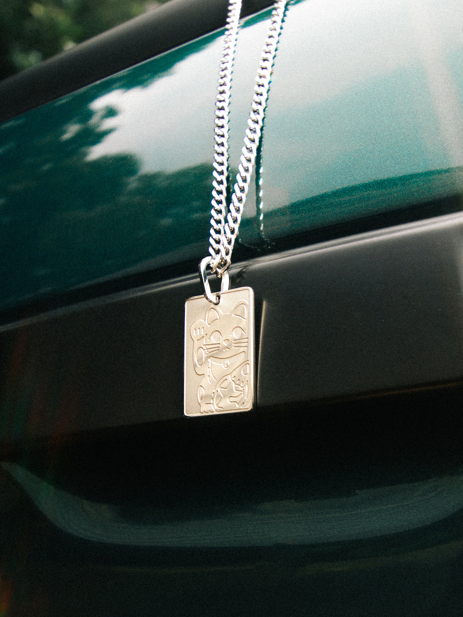 Lucky Cat Necklace resting on a car body