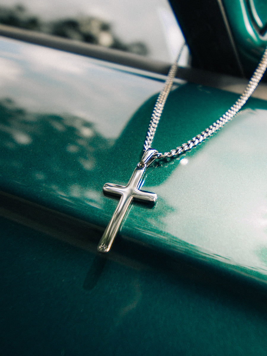 Minimal Cross Necklace resting on a car body
