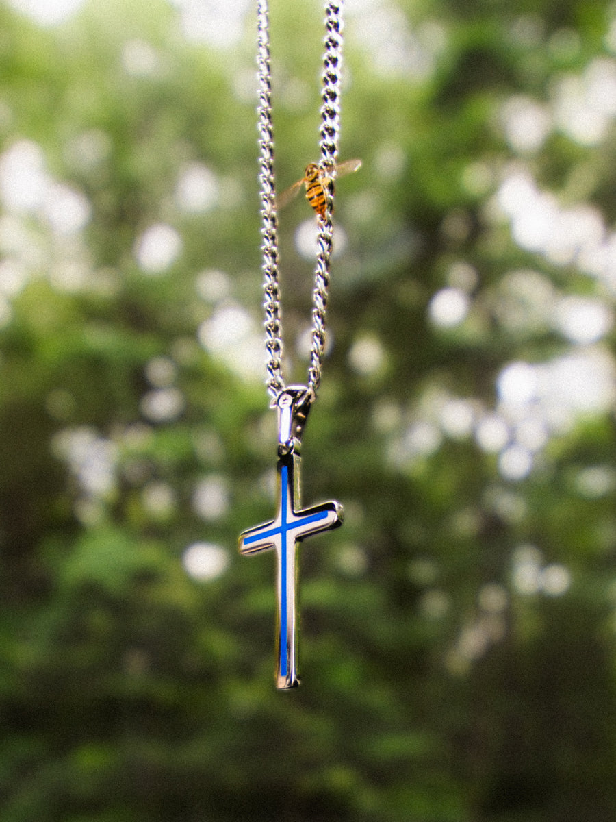 Minimal Cross Necklace photographed against trees